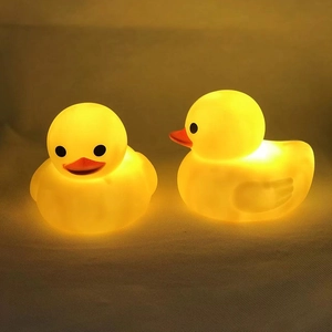 Detailed close-up of two glowing yellow rubber duck night lights with warm silicone texture