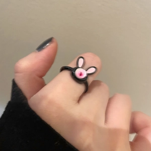 Close-up of a creative black bunny ring with pink enamel detail on a model's hand