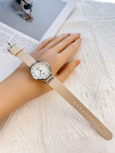 Detailed shot of a minimalist silver quartz watch with beige nylon strap on a magazine background