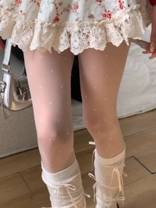 Detail of white polka dot tights with bow accents and lace trim in Lolita style