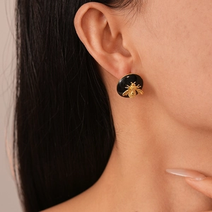 Macro shot of a vintage gold-plated bee stud earring with black enamel detail on ear