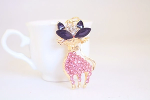 Close-up of pink rhinestone cat keychain with purple crystal eyes and gold-tone base