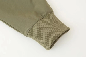 Gros plan détaillé des poignets élastiques vert armée et du tissu tissé de la veste
