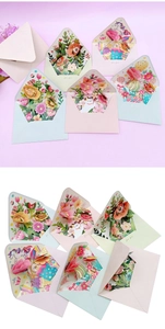 Flat lay of colorful 3D pop-up cards with floral, butterfly and animal designs on pink background