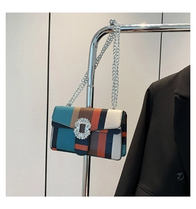 Detailed shot of a striped crossbody bag with rhinestone buckle and silver chain