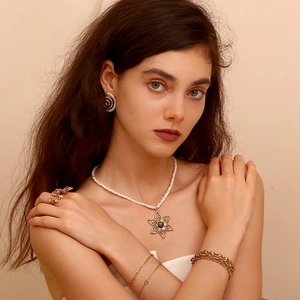 Close-up of 14K gold-plated jewelry set with pearl necklace and petal pendant on model