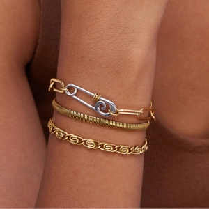 Detail of triple-layered gold bracelet set with safety pin clasp and snake chain texture