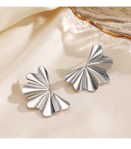 Détail de boucles d'oreilles argentées plissées avec texture ondulée sur soie
