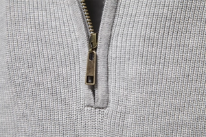 Close-up of a grey ribbed knit sweater featuring a premium bronze half-zip metal neckline