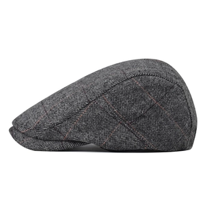 Detail shot of a grey herringbone wool beret with subtle red-brown plaid patterns