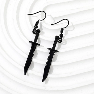 Close-up of black dagger earrings with punk style metallic finish on white background