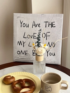 Close-up of textured wall art with romantic script next to home fragrance set
