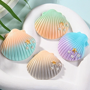 Detailed view of large resin sea shells with pearls and gold stars on a white tray