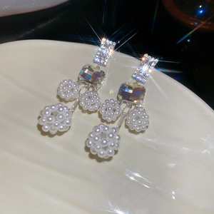 Macro view of long silver drop earrings with crystals and spherical pearl clusters