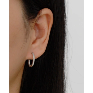 Close-up of a silver S925 hoop earring with pavé diamonds worn on a female ear
