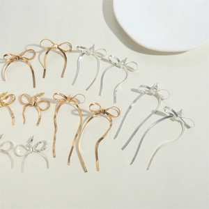 Detail of bowknot tassel earrings in gold and silver finish with snake chain fringe