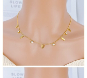 Detailed close-up of a gold leaf pendant necklace with rhinestones on a female model