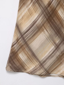 Detail der braun-beigen Karo-Stofftextur mit Saumnaht an einem mittellangen Rock