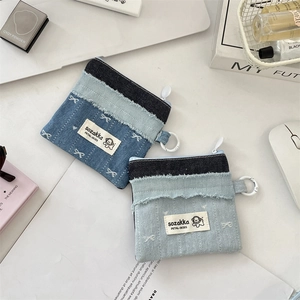 Detail der kleinen Denim-Patchwork-Geldbörse mit niedlichem Welpen-Logo und Metallring