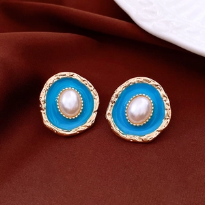 Detail of vintage gold earrings with light blue enamel and central white pearl accent