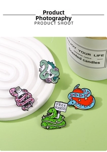 Macro detail of cartoon snake enamel pins with skull and heart motifs on a white tray