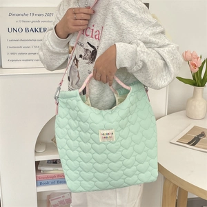 Gros plan d'un sac cabas matelassé vert menthe avec cœurs, sangles roses et étiquette