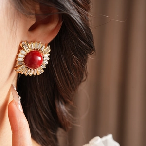Close-up of vintage gold earrings with red round stone and zircon halo on model