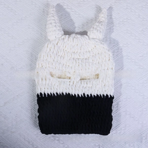 Macro detail of bicolour chunky knit balaclava featuring devil horns and ribbed texture