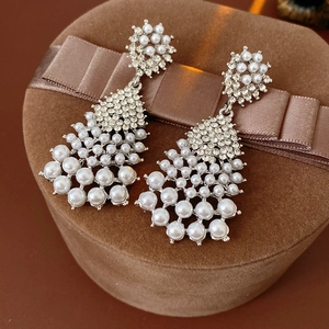 Close-up of luxury vintage earrings with rhinestones and pearls on brown velvet