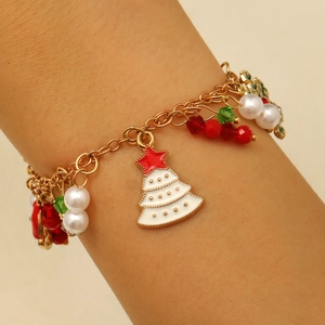 Close-up of golden Christmas charm bracelet with snowflake and tree pendants on wrist