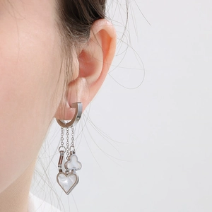 Close-up of heart and clover shell charms on silver tassel earrings worn by model