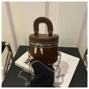 Détail d'un sac cylindre marron foncé vintage avec coutures blanches et chaîne argentée