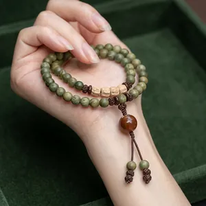 Macro shot of double-wrap beaded bracelet with green crystal beads and a brown tassel