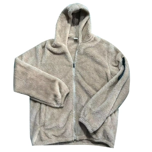 Detail of light beige sherpa fleece jacket featuring a hooded design and sleeve zipper pocket
