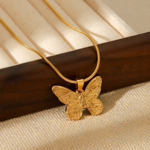 Close-up of golden butterfly pendant with textured wings on a snake bone chain necklace