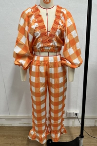 Detail of smocked V-neck crop top and ruffled pants in orange checkered pattern