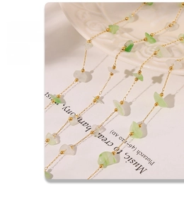 Detail of a gold chain necklace with light green natural stone chips on a white plate