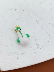 Detailed close-up of a white and green enamel snowman charm with golden metal ring