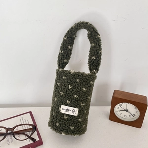 Detail of green plush cup holder bag with white polka dots and soft fabric handle
