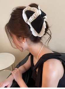 Detail showing a pleated fabric bow hair clip worn by a model in a minimalist style