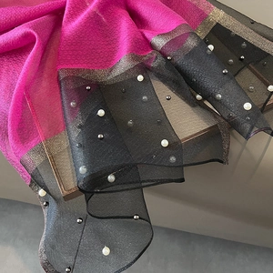 Detailed close-up of fuchsia silk scarf with elegant white pearls and silver bead accents