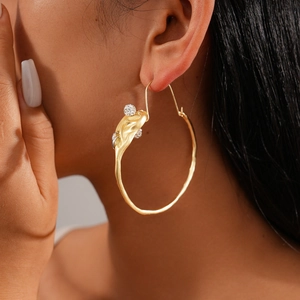 Gros plan de boucles d'oreilles créoles dorées géométriques sur l'oreille d'un modèle