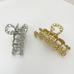 Close-up of gold and silver alloy hair claws with an elegant woven metal texture