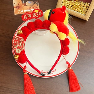 Detail of red New Year headband with cute plush pony, golden ingots and long tassels