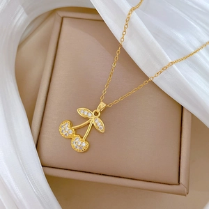 Macro shot of gold cherry pendant necklace with pavé zircon crystals on a jewelry box