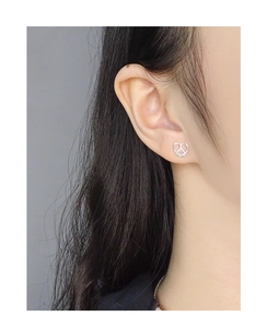Close-up of a model wearing a silver heart-shaped pretzel knot stud earring for women