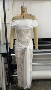 Detailed view of white lace off-shoulder dress with elegant waist tie and intricate floral mesh