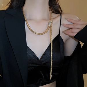 Close-up of sparkling rhinestone snake head and flexible gold chain worn by model