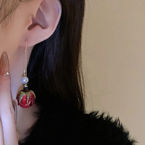 Vue détaillée de la boucle d'oreille rose rouge avec perle sur une chaîne dorée