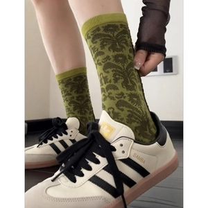 Detail view of retro cotton blend mid-calf socks with green scroll patterns on a model